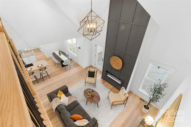 living room with an inviting chandelier, a fireplace, light hardwood / wood-style floors, and vaulted ceiling