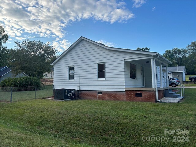 view of side of home with central AC unit and a yard