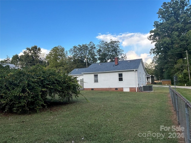 rear view of house with cooling unit and a lawn