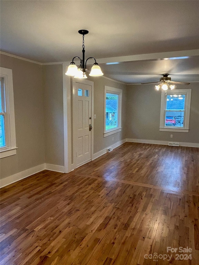 foyer entrance featuring ceiling fan with notable chandelier, crown molding, dark hardwood / wood-style floors, and a wealth of natural light