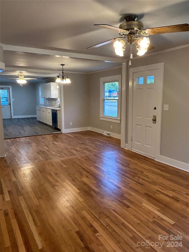 unfurnished living room featuring ceiling fan with notable chandelier, dark hardwood / wood-style floors, ornamental molding, and sink