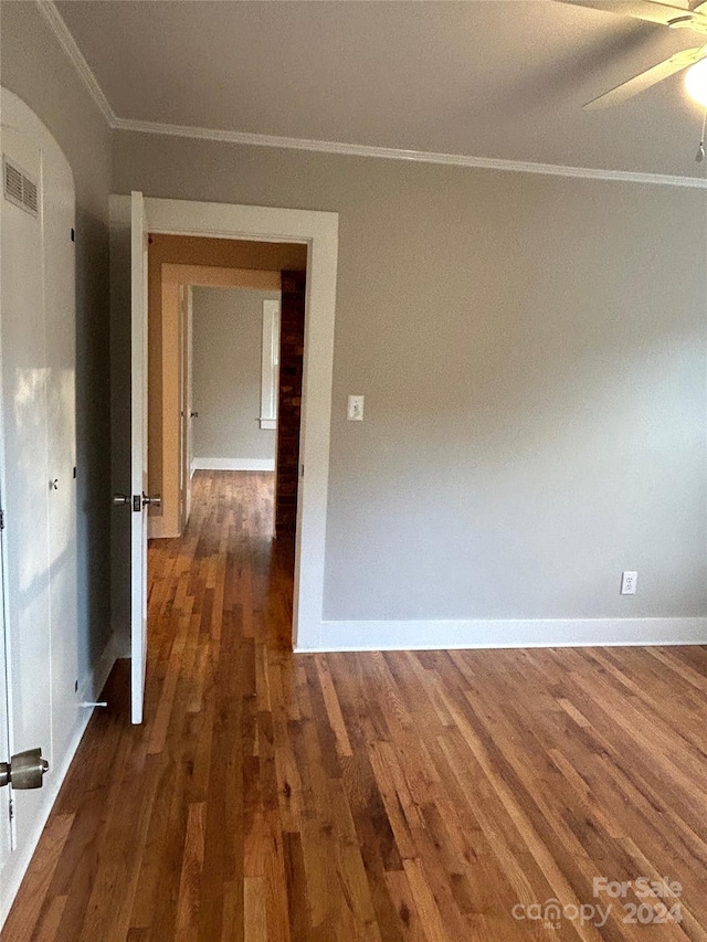 empty room featuring ornamental molding, dark wood-type flooring, and ceiling fan