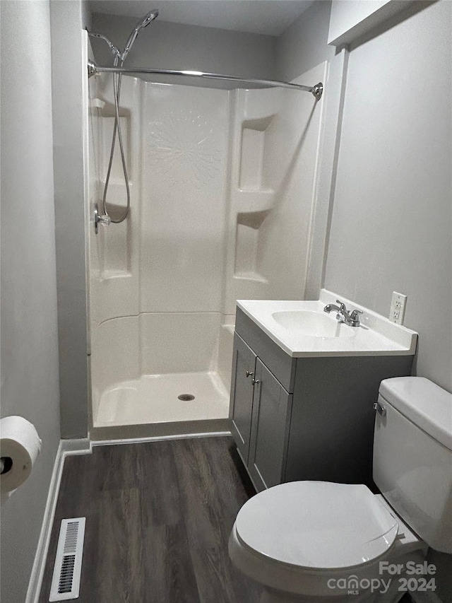 bathroom with a shower, vanity, toilet, and hardwood / wood-style floors