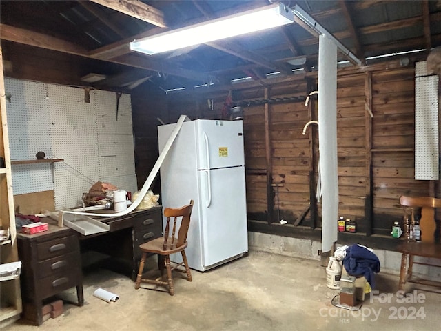 basement with wooden walls and white refrigerator