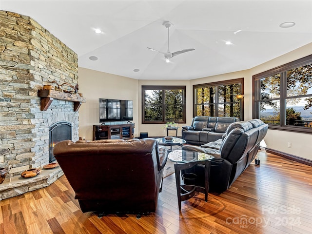 living room with wood-type flooring, vaulted ceiling, ceiling fan, and a fireplace