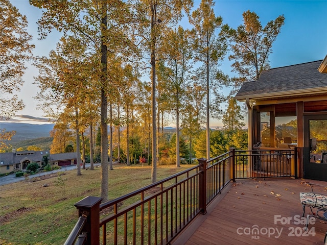 deck at dusk featuring a lawn