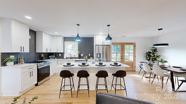 kitchen featuring pendant lighting, stainless steel appliances, a center island, and white cabinets