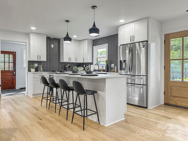 kitchen with pendant lighting, stainless steel fridge with ice dispenser, and white cabinets