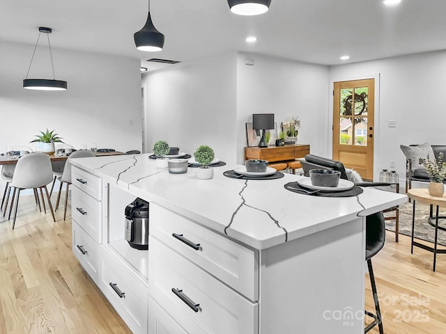 kitchen with a center island, pendant lighting, and white cabinets