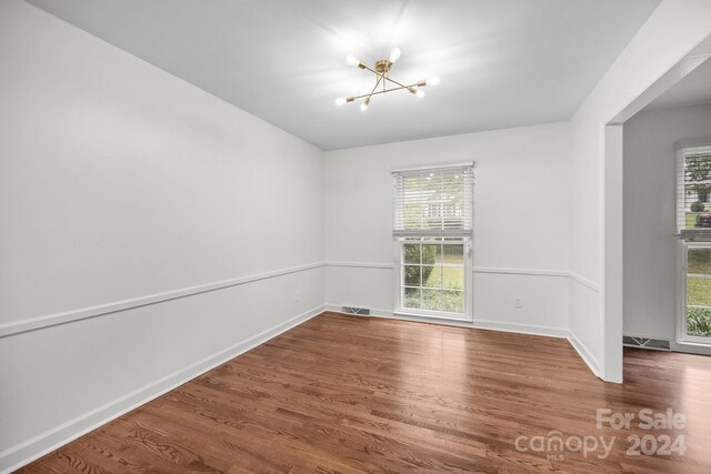 spare room with a chandelier and hardwood / wood-style flooring