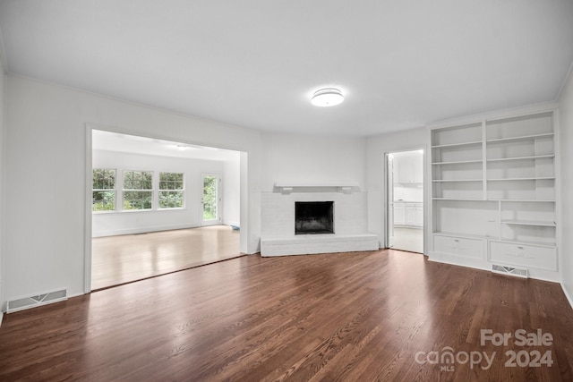 unfurnished living room featuring a brick fireplace and hardwood / wood-style floors