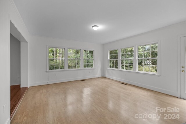 empty room featuring light wood-type flooring and crown molding