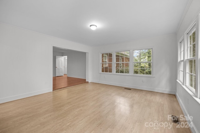 unfurnished room featuring light wood-type flooring and crown molding