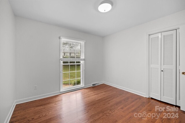 unfurnished bedroom with a closet and hardwood / wood-style flooring