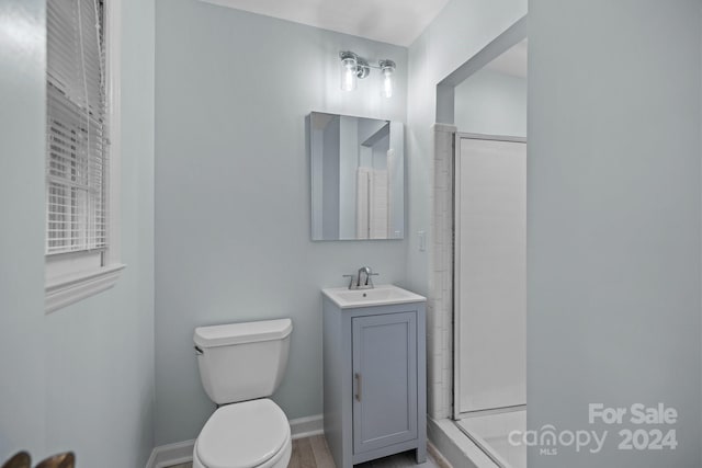 bathroom with hardwood / wood-style flooring, vanity, toilet, and a shower with door