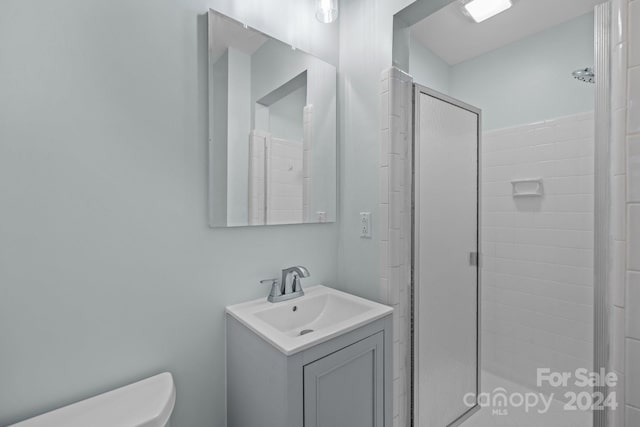 bathroom featuring tiled shower, vanity, and toilet