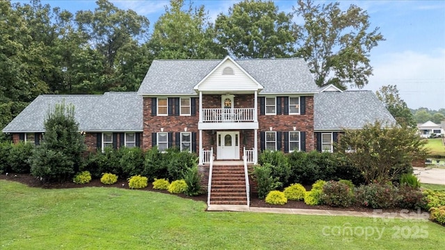 colonial house with a balcony and a front yard