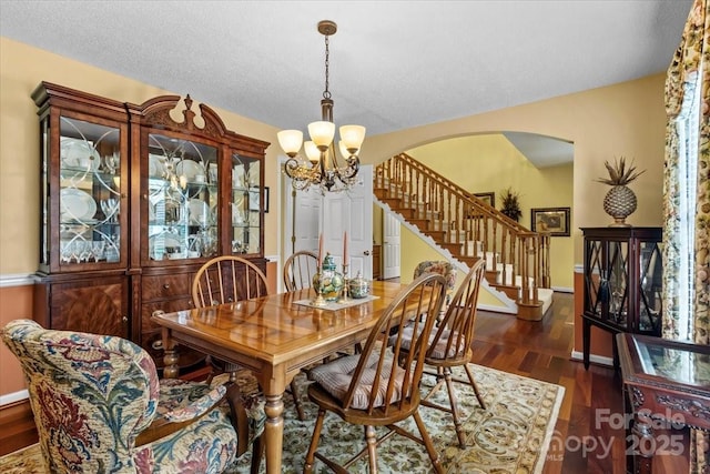 dining area with a textured ceiling, dark hardwood / wood-style flooring, and a notable chandelier