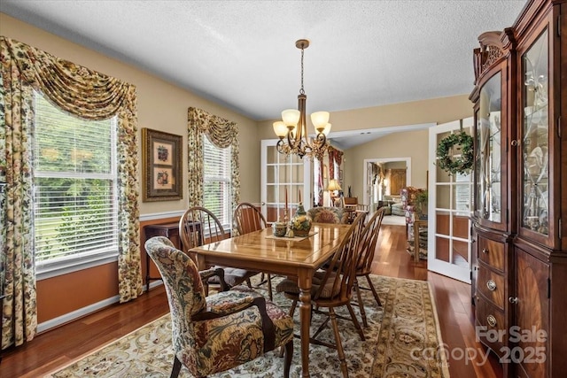 dining area featuring a textured ceiling, dark hardwood / wood-style flooring, and a notable chandelier