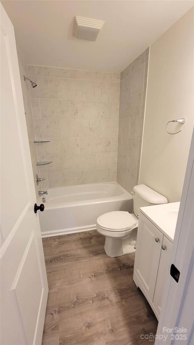 full bathroom featuring vanity, toilet, tiled shower / bath combo, and hardwood / wood-style floors