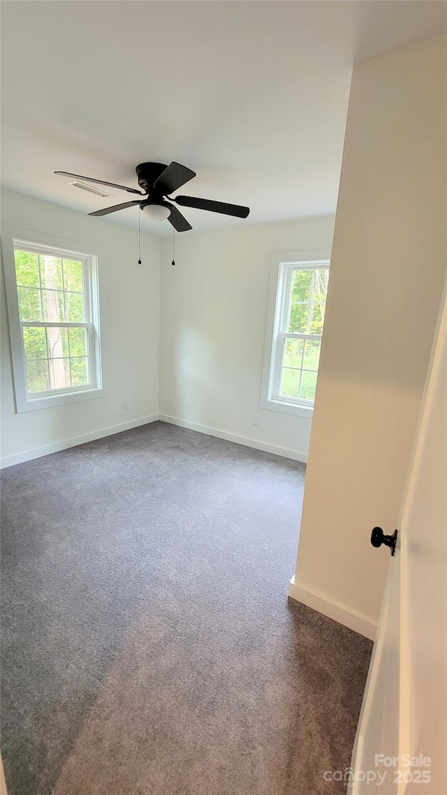 spare room with dark colored carpet, plenty of natural light, and ceiling fan