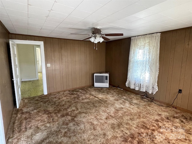 unfurnished room with carpet floors, wood walls, and ceiling fan