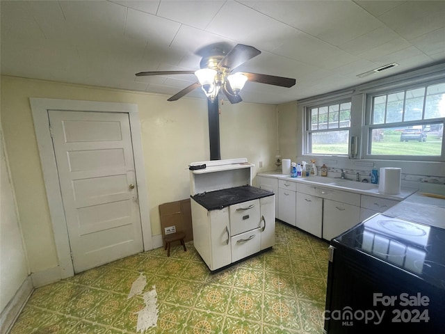 kitchen featuring black / electric stove, sink, ceiling fan, and white cabinets