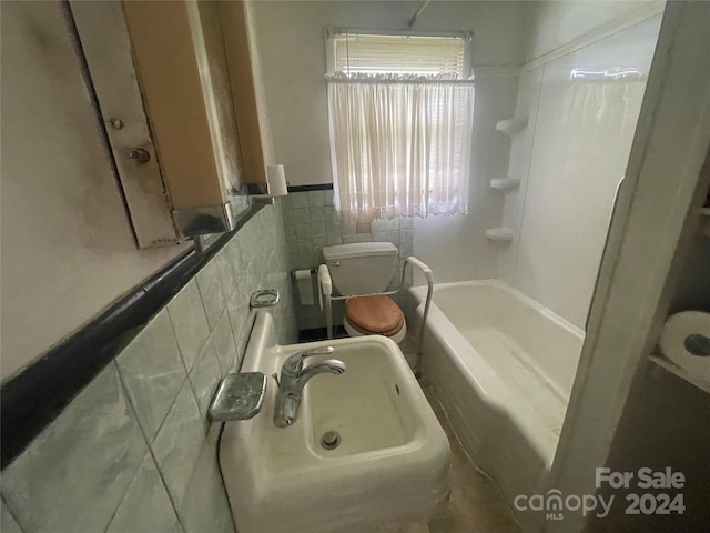 bathroom featuring tile walls, a tub to relax in, and toilet