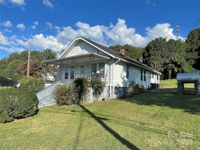 view of side of property with a lawn, central air condition unit, and covered porch