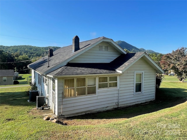 view of home's exterior with cooling unit and a yard