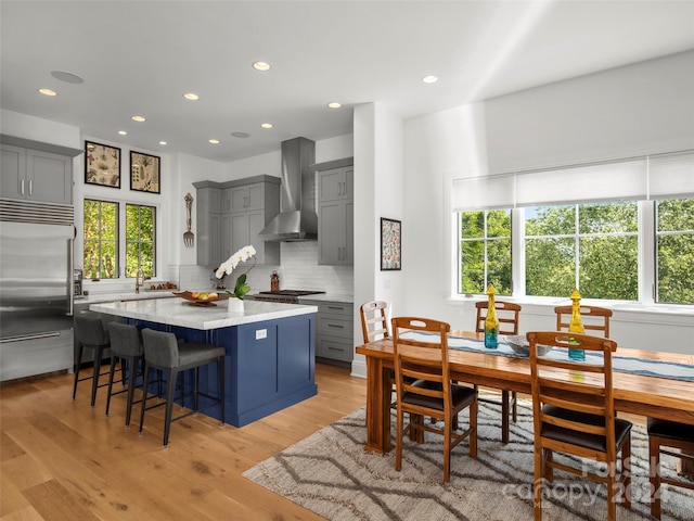 4 Windelsham Way, Arden, NC 28704 - kitchen featuring stainless steel appliances, gray cabinetry, wall chimney range hood, a kitchen island, and light hardwood / wood-style flooring