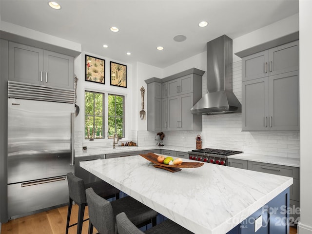 4 Windelsham Way, Arden, NC 28704 - kitchen featuring stainless steel appliances, a kitchen island, wall chimney range hood, a kitchen breakfast bar, and light hardwood / wood-style floors