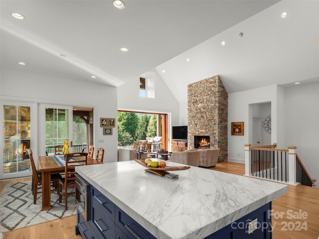 4 Windelsham Way, Arden, NC 28704 - kitchen featuring blue cabinets, a stone fireplace, light wood finished floors, recessed lighting, and high vaulted ceiling