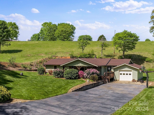 single story home featuring a front lawn, a rural view, and a garage