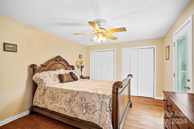 bedroom featuring a textured ceiling, two closets, ceiling fan, and light hardwood / wood-style flooring