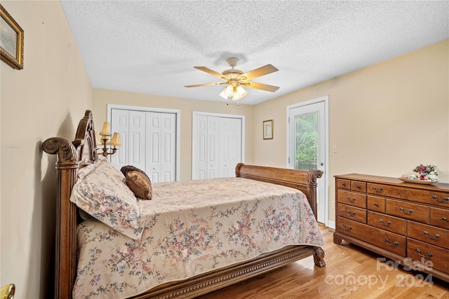 bedroom featuring ceiling fan, a textured ceiling, two closets, and hardwood / wood-style floors