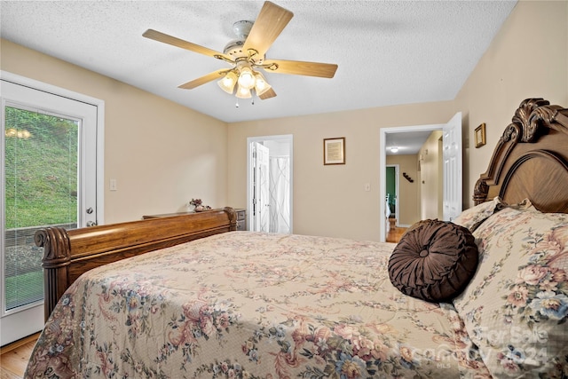 bedroom with ceiling fan, hardwood / wood-style flooring, a textured ceiling, and multiple windows