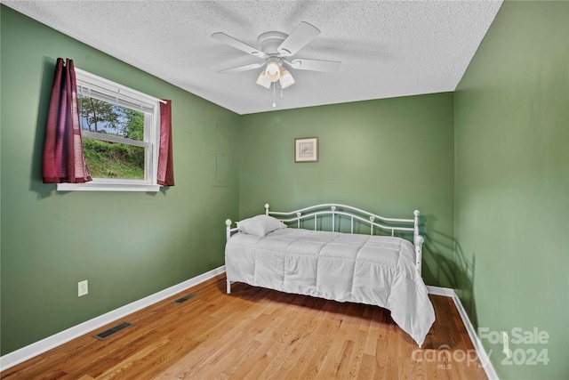 bedroom featuring a textured ceiling, light hardwood / wood-style floors, and ceiling fan