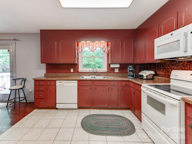 kitchen featuring white appliances, sink, light tile patterned floors, and a wealth of natural light