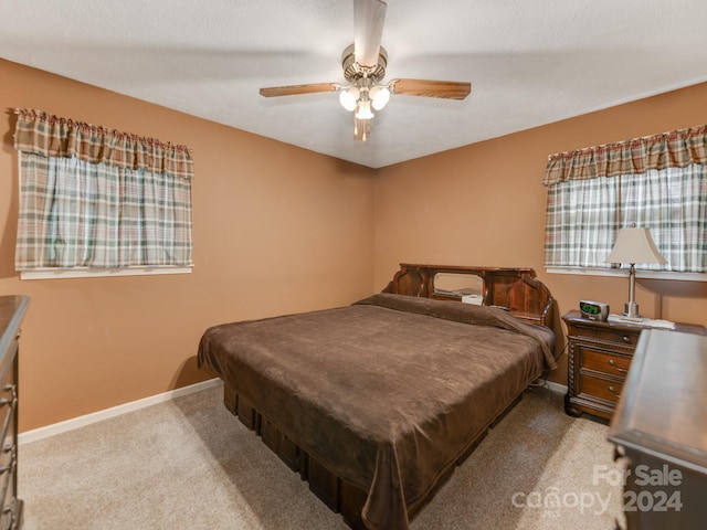 carpeted bedroom with ceiling fan and a textured ceiling