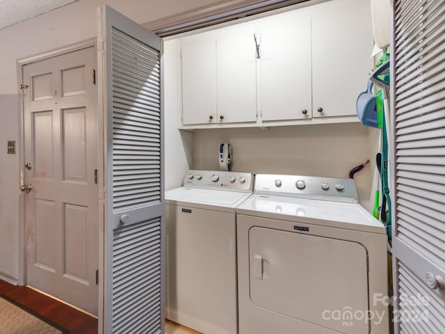 clothes washing area featuring cabinets, light wood-type flooring, and washing machine and dryer