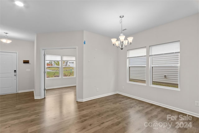 unfurnished dining area featuring a notable chandelier and dark hardwood / wood-style flooring