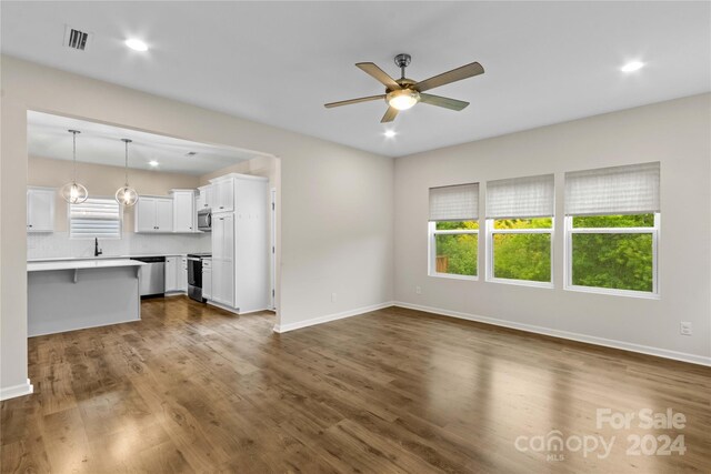 unfurnished living room with ceiling fan, dark wood-type flooring, and sink