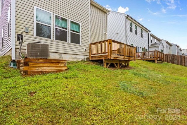 rear view of property with a lawn, cooling unit, and a wooden deck