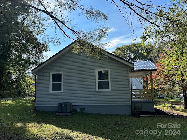 view of side of home featuring cooling unit and a yard