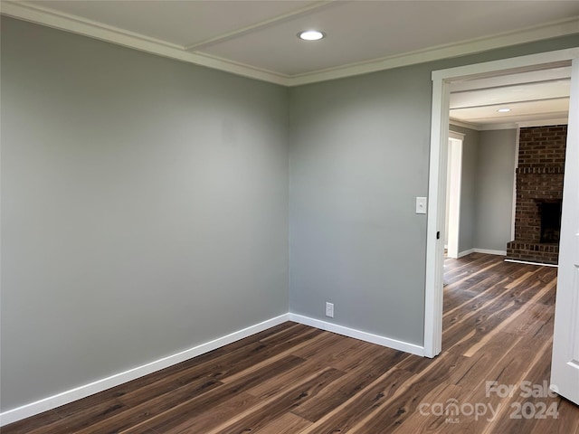 empty room with crown molding, a fireplace, and dark wood-type flooring