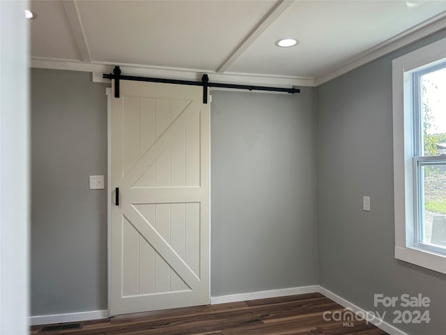 interior space with a barn door, crown molding, and dark wood-type flooring