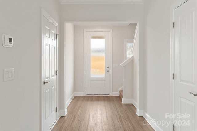 foyer entrance with light wood-type flooring and crown molding