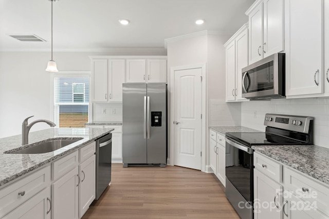 kitchen featuring appliances with stainless steel finishes, white cabinetry, pendant lighting, light hardwood / wood-style flooring, and sink