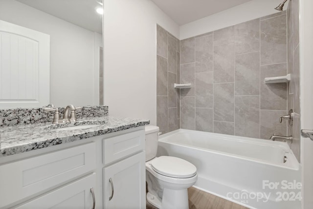 full bathroom featuring hardwood / wood-style floors, tiled shower / bath, vanity, and toilet